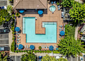 Thumbnail 7 of 20 - An aerial view of a pool surrounded by trees and chairs.
