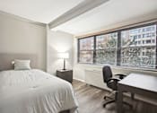 Thumbnail 5 of 20 - a bedroom with a bed and a desk and a large window