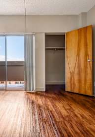 A room with a wooden floor and a sliding glass door leading to a balcony.