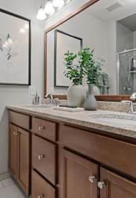 A bathroom with a white toilet, a sink with a marble countertop, and a large mirror.