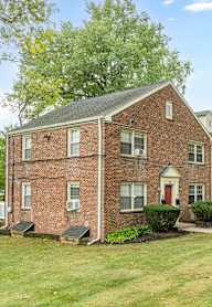A red brick house with a white fence in front.