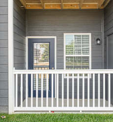 A small porch with a white railing and a door with a window above it.