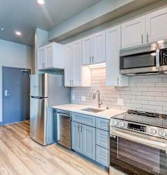 A kitchen with white cabinets and a stainless steel refrigerator.