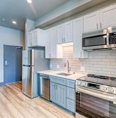 A kitchen with white cabinets and a stainless steel refrigerator.