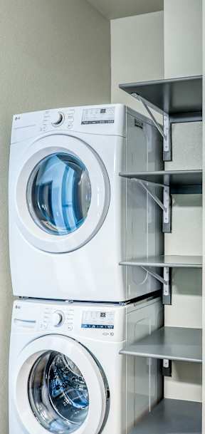 A white washing machine is stacked on top of another in a laundry room.