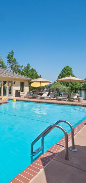 a swimming pool with lounge chairs and umbrellas in front of a building