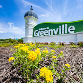 A sign that says Greenville in front of a white dome.