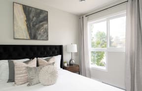 a bedroom with a large window and a large bed with a black tufted headboard