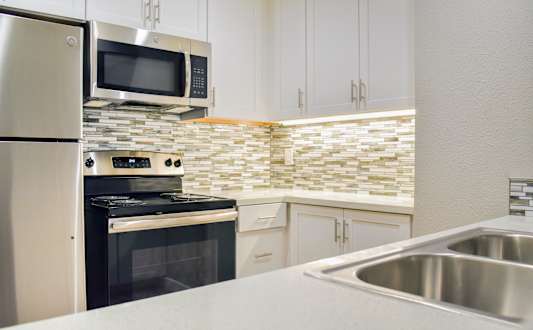 A kitchen with a stove, oven, microwave, and cabinets.