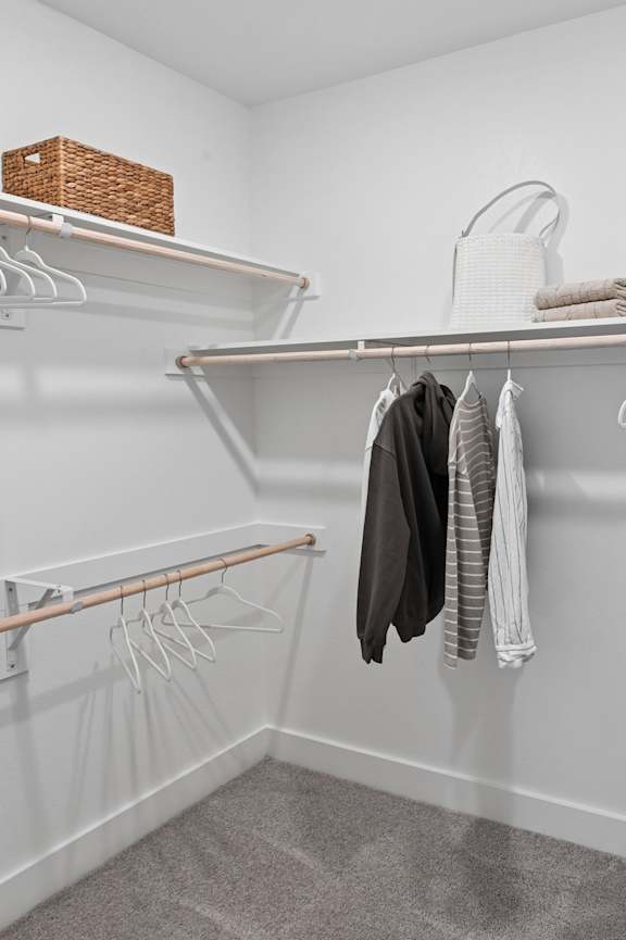 A white closet with clothes hanging on hangers.