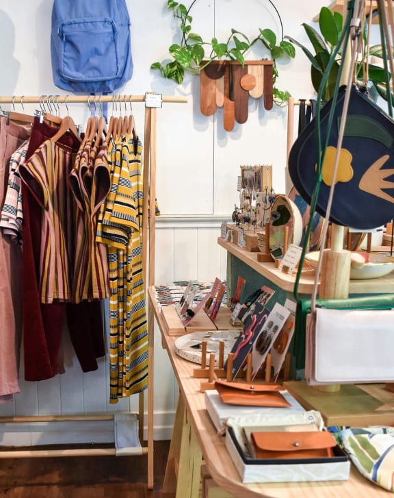 a clothing store with clothes hanging on a rack and a table with accessories
