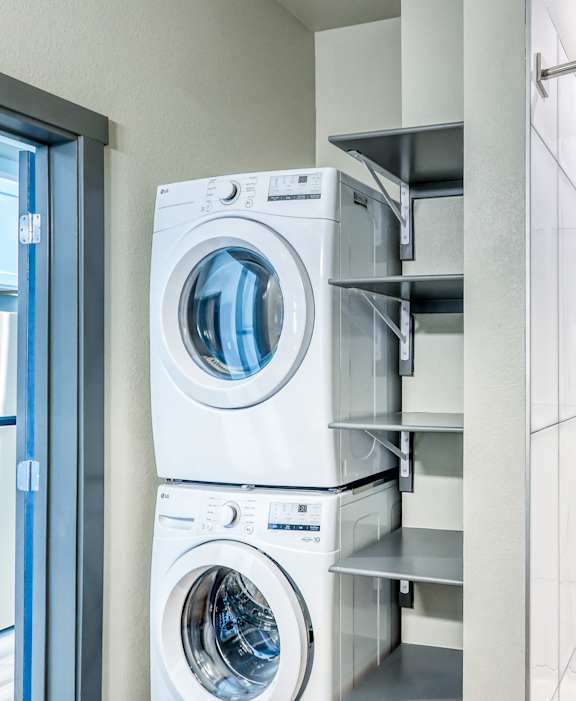 A white washing machine is stacked on top of another in a laundry room.