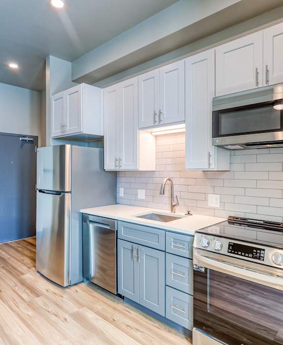 A kitchen with white cabinets and a stainless steel refrigerator.