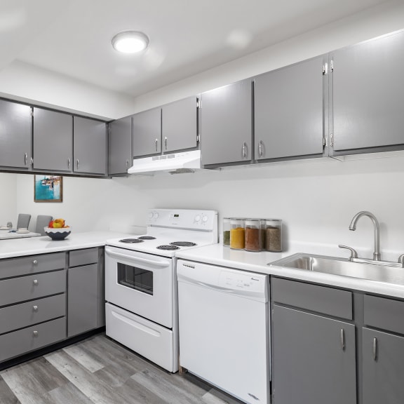 L shaped kitchen with white appliances and modern grey cabinets