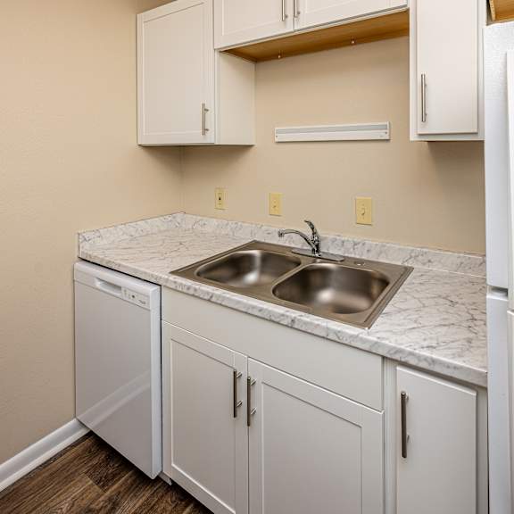 A kitchen with white cabinets and a marble countertop.