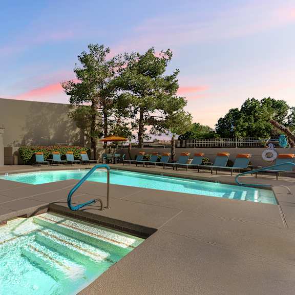 A swimming pool with a slide and lounging chairs.