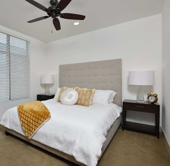 A bedroom with a bed, nightstands, and a ceiling fan.