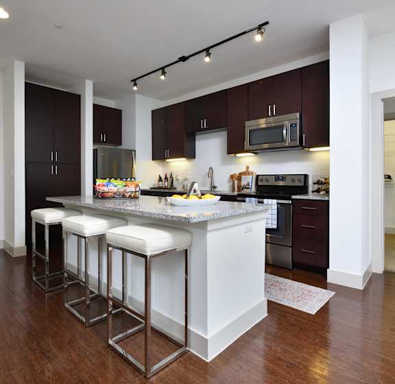 A kitchen with a white island and bar stools.