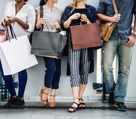A group of people standing together holding shopping bags.