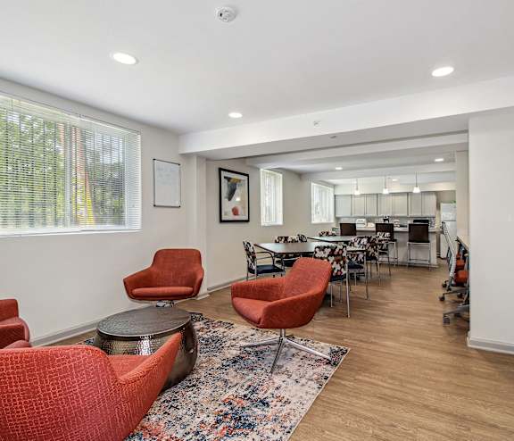 a living room with red chairs and a dining room with tables and chairs