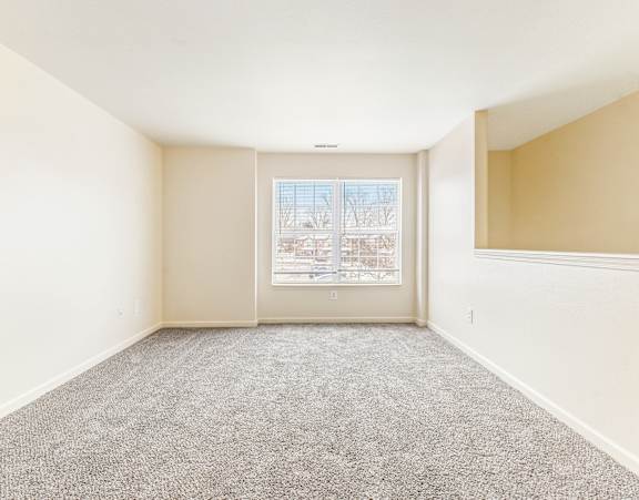 A room with a carpeted floor and a window showing a snowy landscape outside. at Northampton Village Apartments, Indianapolis, Indiana