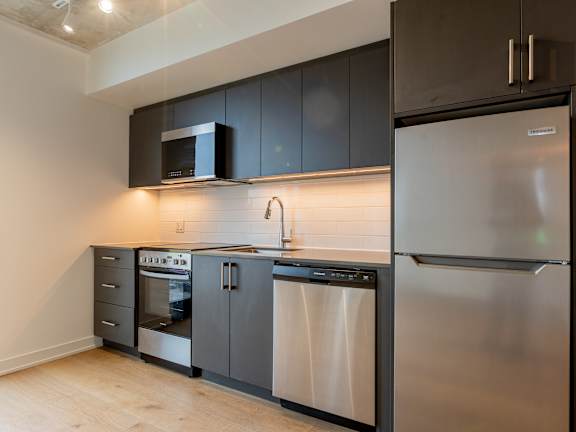 A modern kitchen with stainless steel appliances and dark brown cabinets.