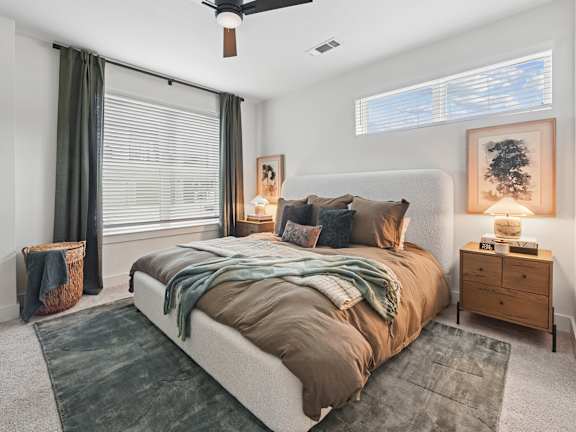 A bedroom with a large bed and a ceiling fan.