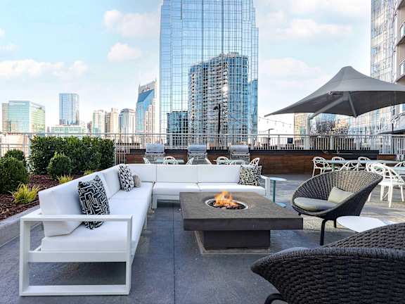 A patio with a fire pit and seating area overlooking a city skyline.