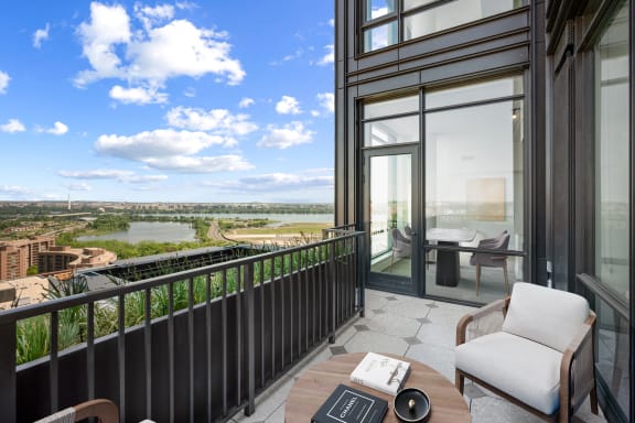 a balcony with a chair and a table overlooking a river