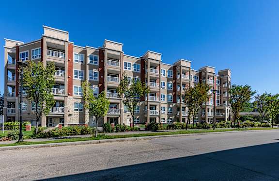A row of apartment buildings with trees in front.