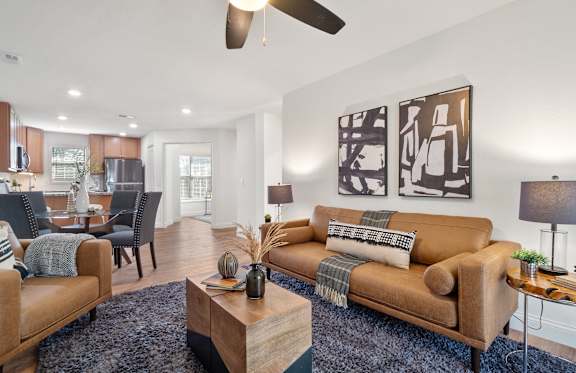 A living room with a brown couch and a ceiling fan.