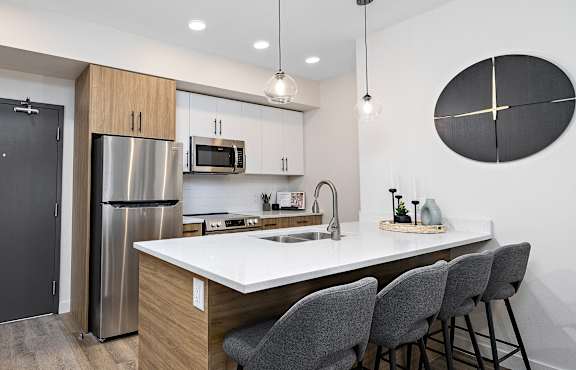 A modern kitchen with a large island and grey chairs.