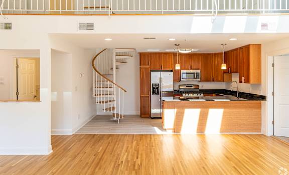 A modern kitchen with wooden cabinets and a spiral staircase.