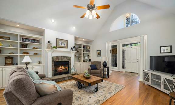 A living room with a fireplace and a ceiling fan.