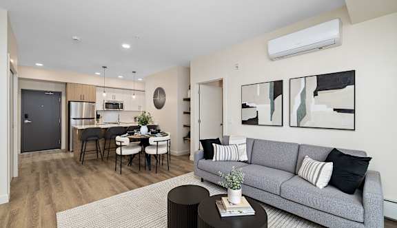 A modern living room with a grey sofa and a dining table.at The Fifth at Palisades, Edmonton, AB, T6V 0N5