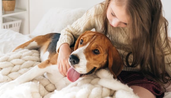 a girl and her dog laying on a bed