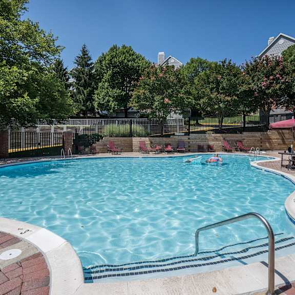 A swimming pool surrounded by a brick border and a metal fence.