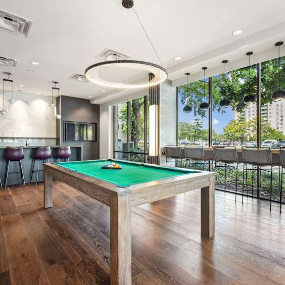A billiard table in a room with a bar and a balcony.