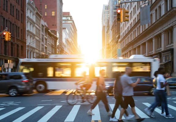 people crossing a busy city street with a bus