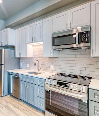 A kitchen with white cabinets and a stainless steel refrigerator.