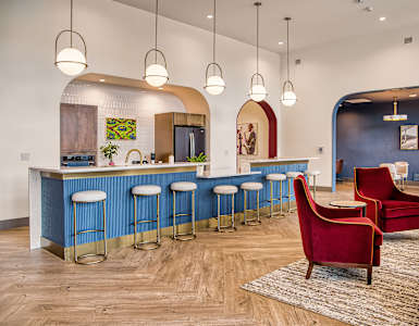 A blue bar with stools and a red chair in front of it.