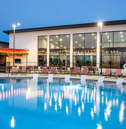A swimming pool in front of a building with a red awning.