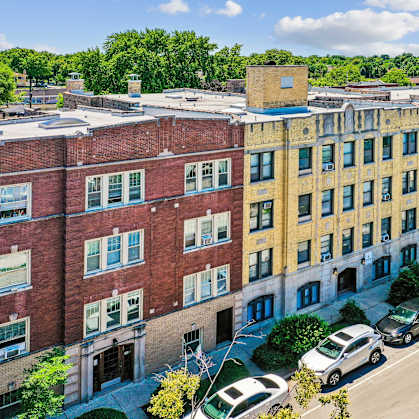 A street view of a row of buildings with cars parked on the street.