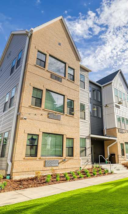 A modern apartment complex with a well-maintained lawn in front.