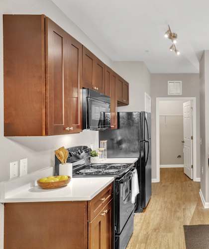 A kitchen with brown cabinets and a black refrigerator.