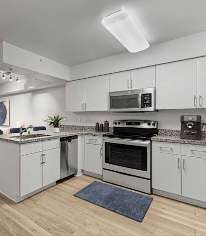 A modern kitchen with white cabinets and a wooden floor.