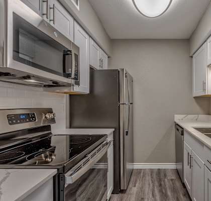 A kitchen with a stove, microwave, refrigerator, and sink.