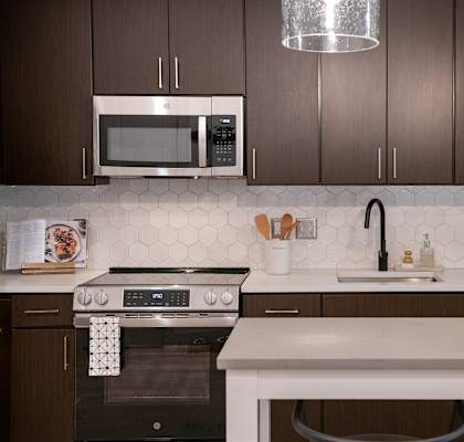A modern kitchen with dark brown cabinets and a white countertop.