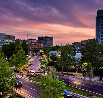 A city street at dusk with cars driving and buildings in the background. at Somerset at Towson Apartments, Towson, MD, 21204