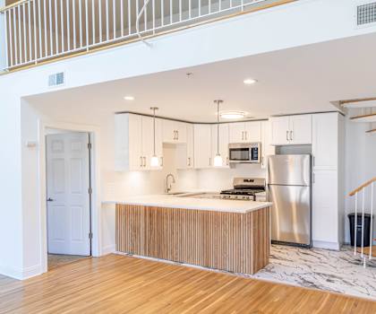 A modern kitchen with a wooden floor and stainless steel appliances.